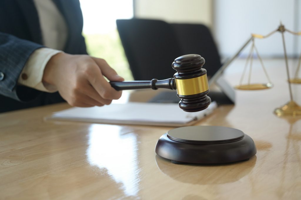 Concept of justice, Lawyer holding a hammer pretending to hit on a wooden tray put on the desk.