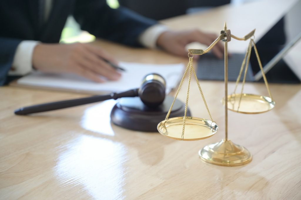 Concept of justice, Lawyer holding a hammer pretending to hit on a wooden tray put on the desk.