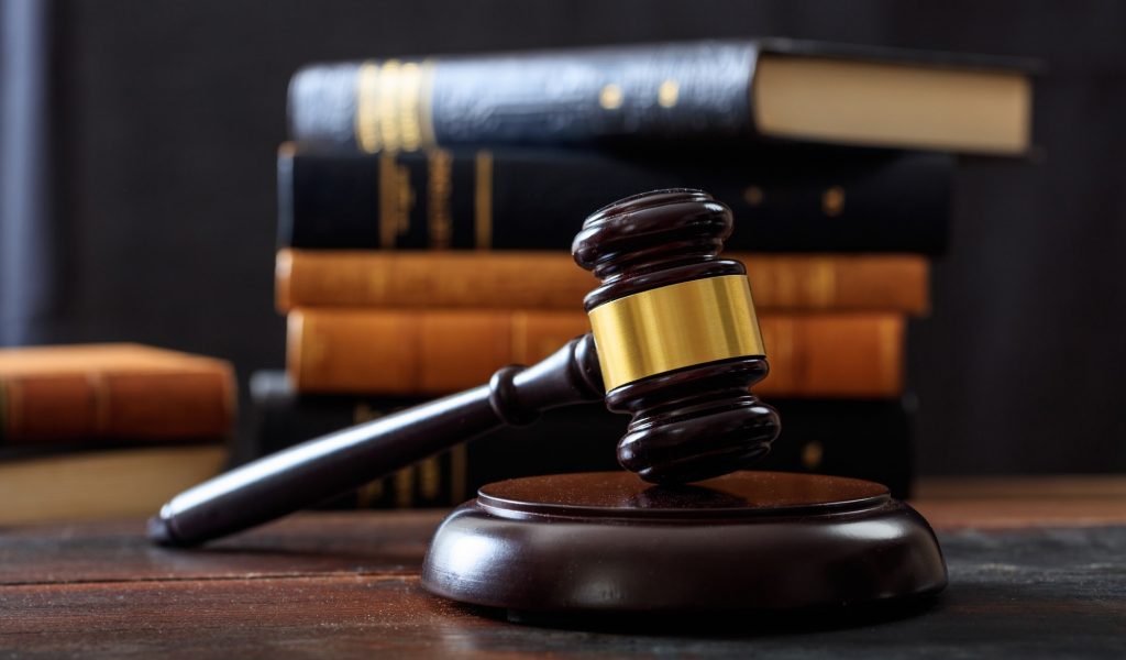 Judge gavel on a wooden desk, law books background