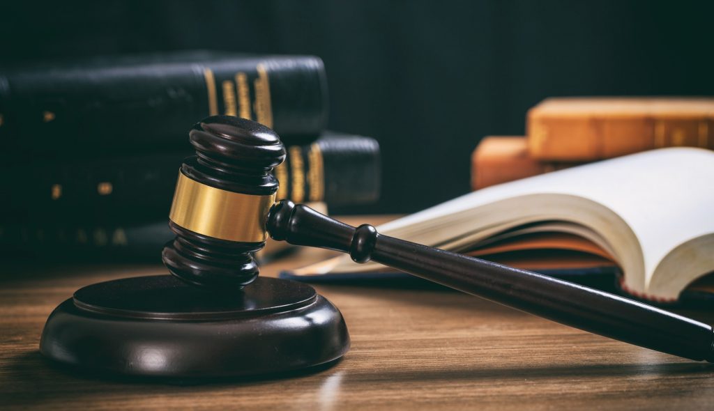 Judge gavel on a wooden desk, law books background