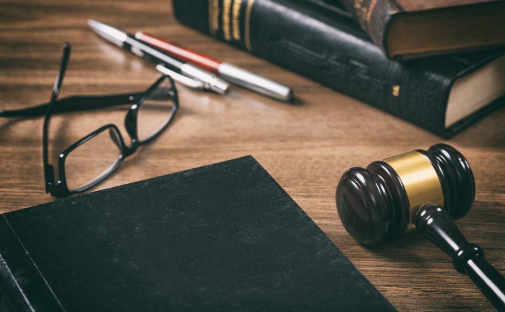 Law or auction gavel and a book, wooden office desk background. Closeup view, space for text